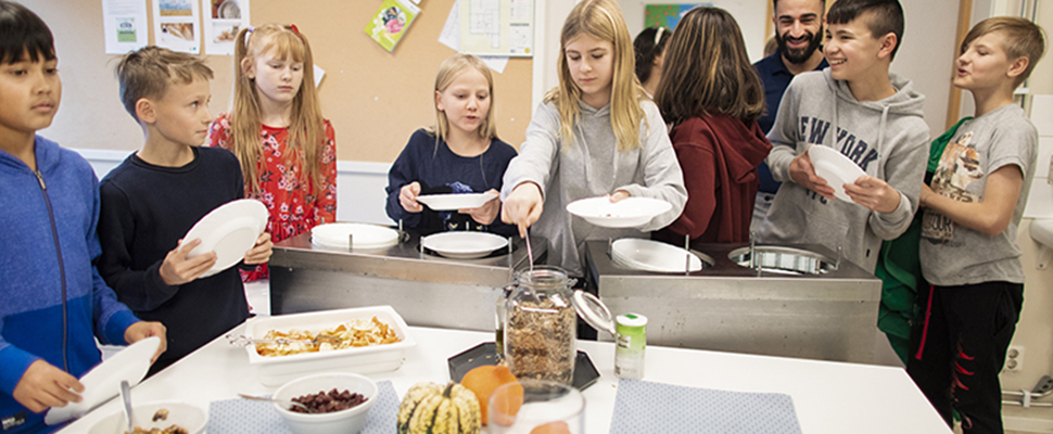 Skolelever som tar sig mat i skolmatsalen.